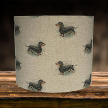 Load image into Gallery viewer, Beige linen lampshade adorned with charming sausage dog illustrations, enhancing room decor.